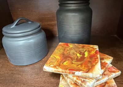 Two black cannisters paired with hand glazed coasters set of four image