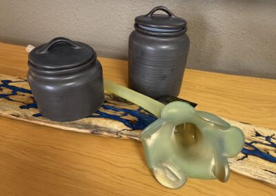 Two black ceramic canisters with a long stem blown glass flower image